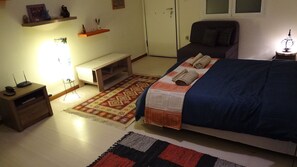 A bedroom with a bed, bedside tables, a desk, a chair, a rug, and a door. - Apartment at Lykavitos 1 bed 2 pers (Athens)