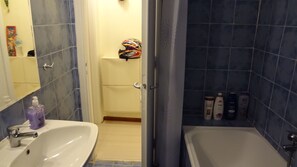A bathroom with a white sink, a bathtub, and a shower area. There are toiletries on the wall. - Apartment at Lykavitos 1 bed 2 pers (Athens)