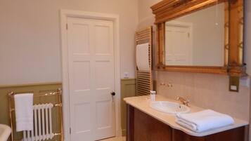A bathroom with a white door, a radiator, a wooden vanity with a sink, and a large mirror.