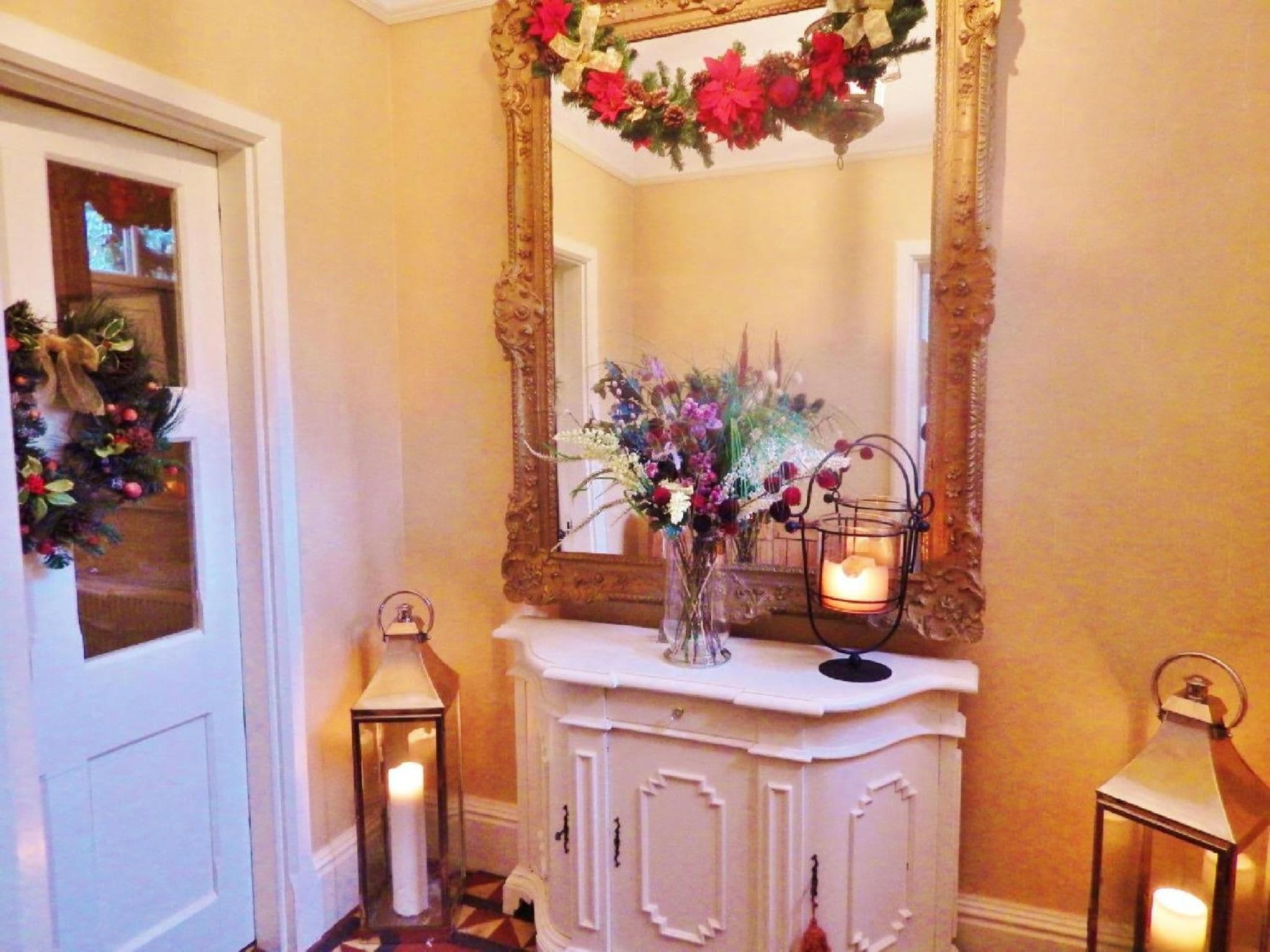 A hallway with a white console table, a large mirror, and two wall-mounted lanterns.