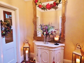 A hallway with a white console table, a large mirror, and two wall-mounted lanterns. - Westgate Manor (Bishop Auckland)