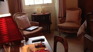 A cozy room with a wooden table, two chairs, a lamp, and a window with curtains. - Westgate Manor (Bishop Auckland)