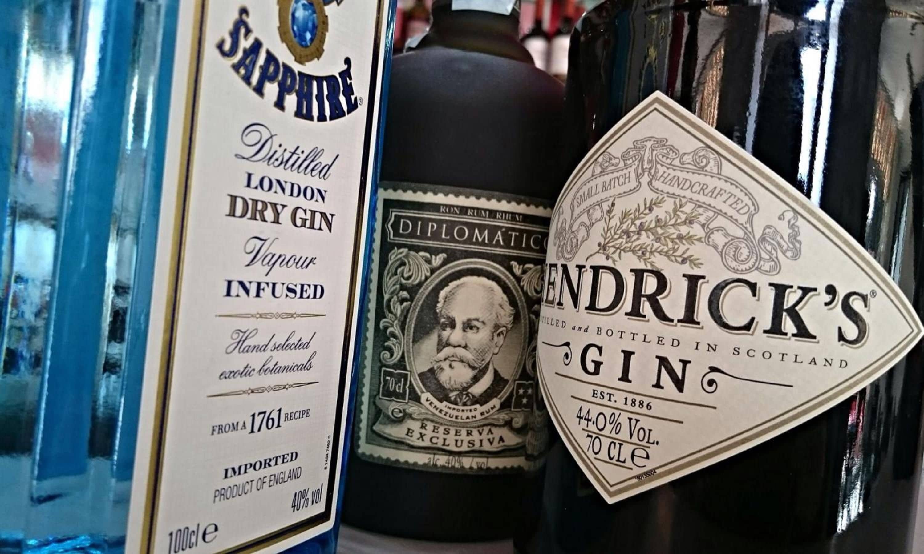 Una colección de botellas de alcohol, incluyendo una botella de ginebra Hendrick's y una botella de ron Diplomático.