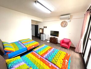 A hotel room with two beds, a TV, a red chair, and a clock on the wall. - Qili Homestay (Chaozhou)