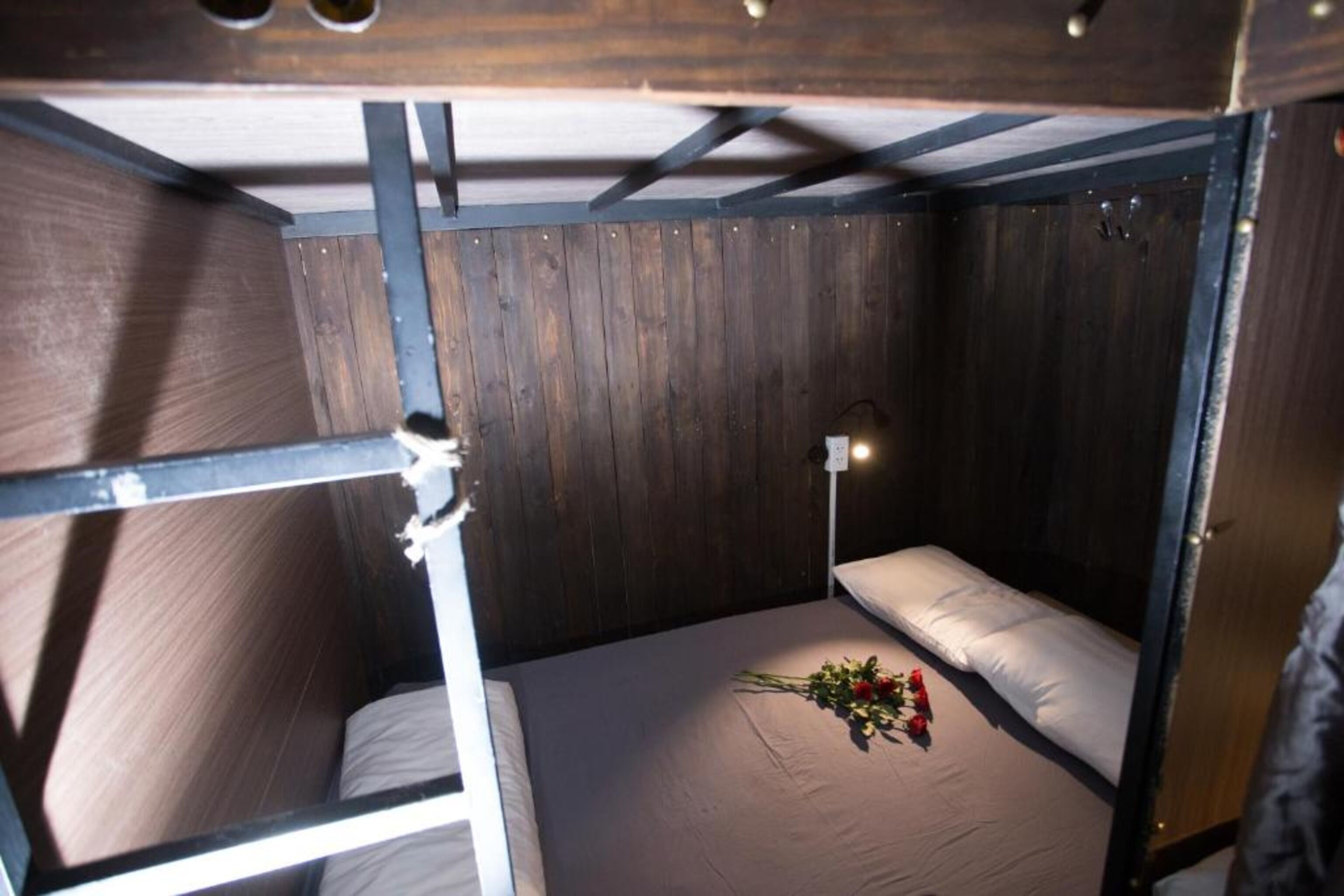 Una camera con letto a castello, pareti in legno e un comodino con lampada.
