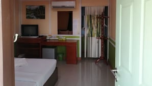 Une chambre d’hôtel équipée d’un lit, d’un bureau, d’une télévision, d’un appareil de climatisation et d’une porte avec un rideau.