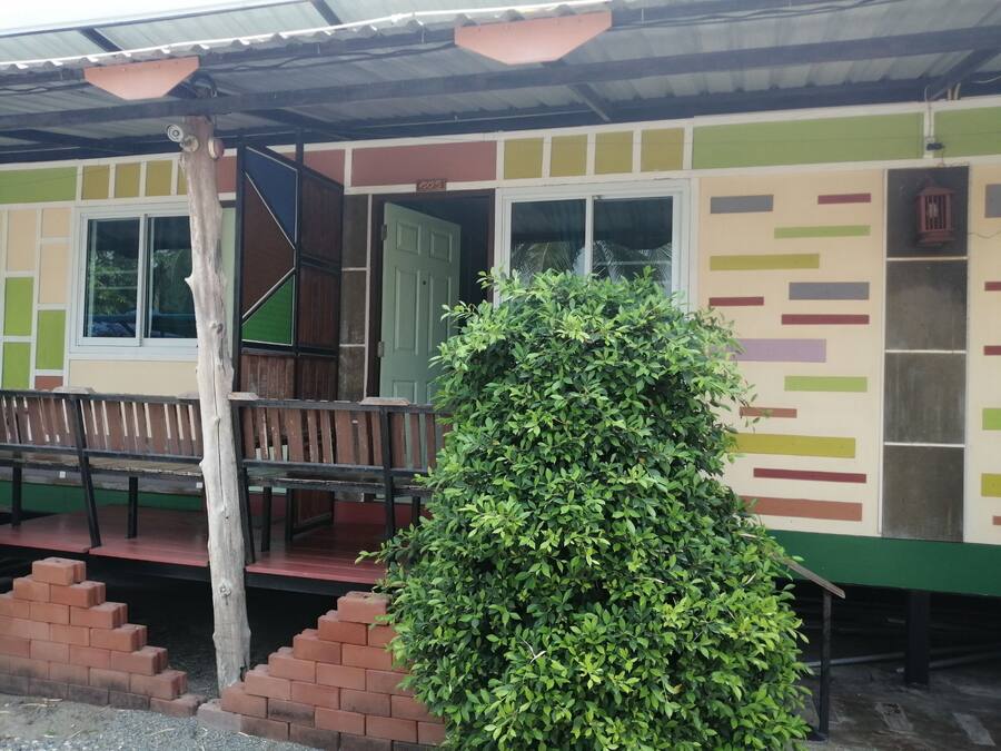 Un edificio de fachada verde y beige, con un banco de madera y una escalera que conduce a una puerta con el número 205.