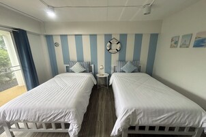 A room with two single beds, a small round table, and a view of the outdoors.