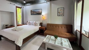 A hotel room with a bed, a sofa, a small table with decorative items, a lamp, and two framed pictures on the walls. - Tann Anda Resort (Thep Krasattri)