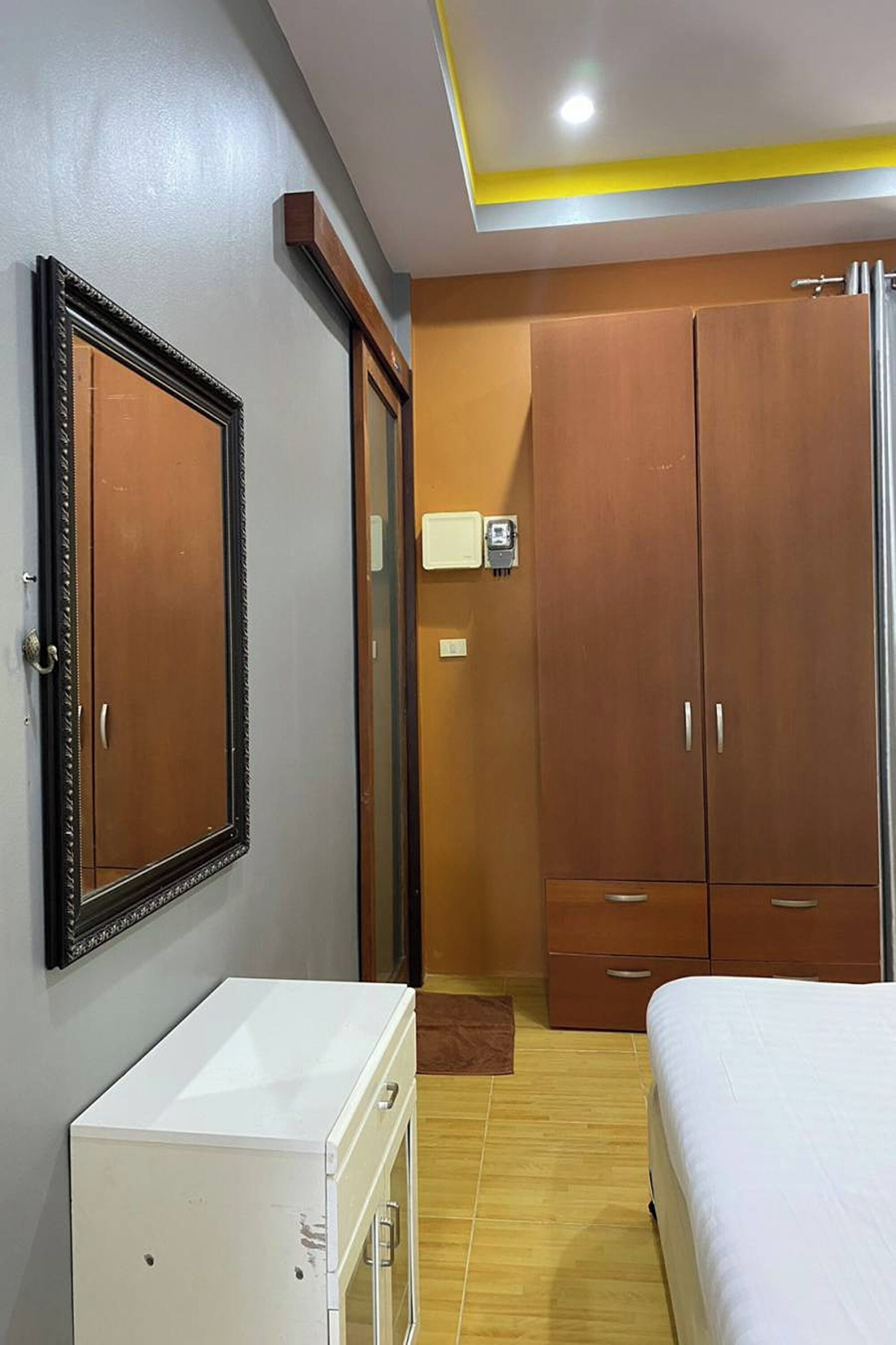 Una habitación de hotel con cama, armario y un pequeño mueble blanco.