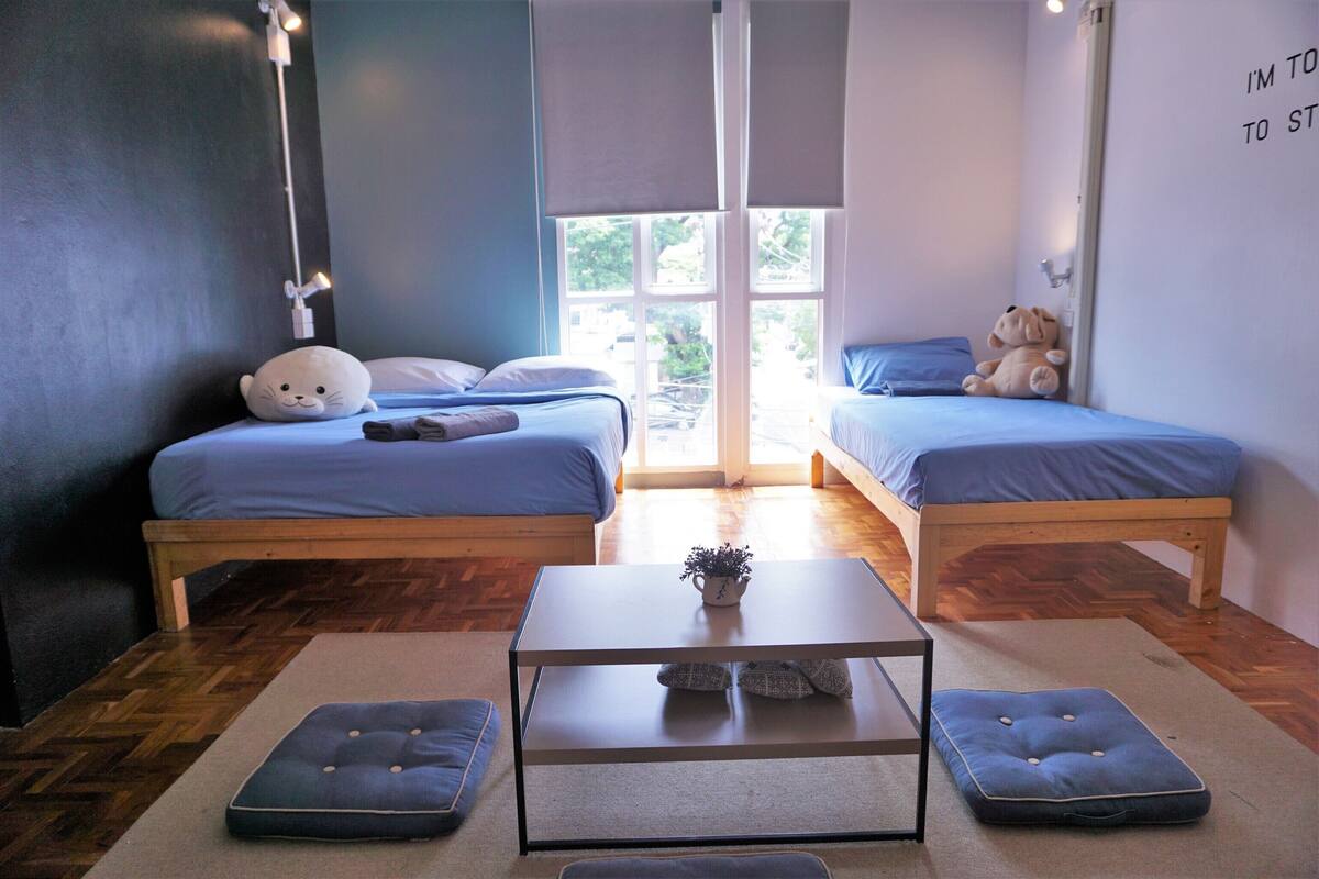A room with two beds, a small table, and a window.