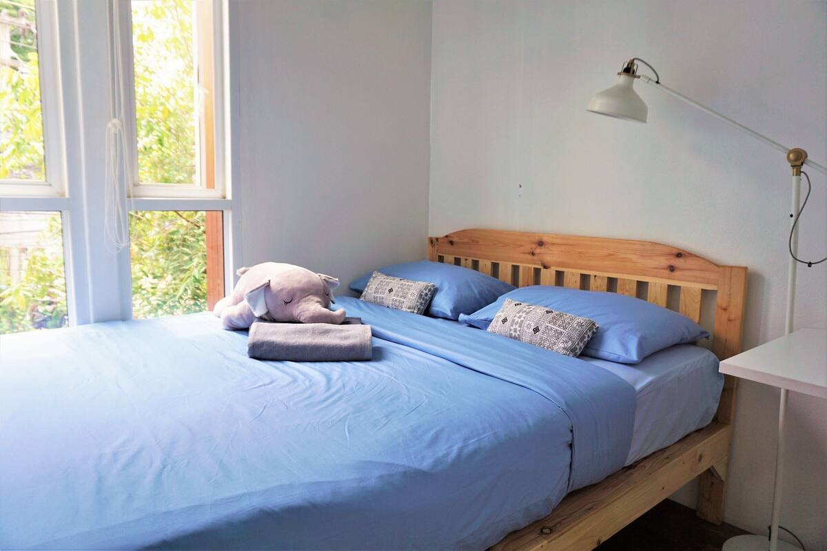 A bed with blue bedding, a wooden headboard, and a bedside lamp.