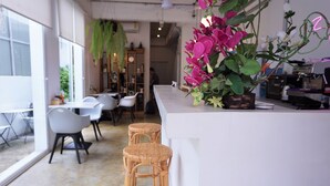 Et moderne interiør med barområde, fletstole og en stor blomsterdekoration.