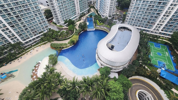 A high-rise building with a swimming pool, palm trees, and a basketball court. - Azure Staycation Philippines by AMRS Near Manila International Airport (Parañaque)