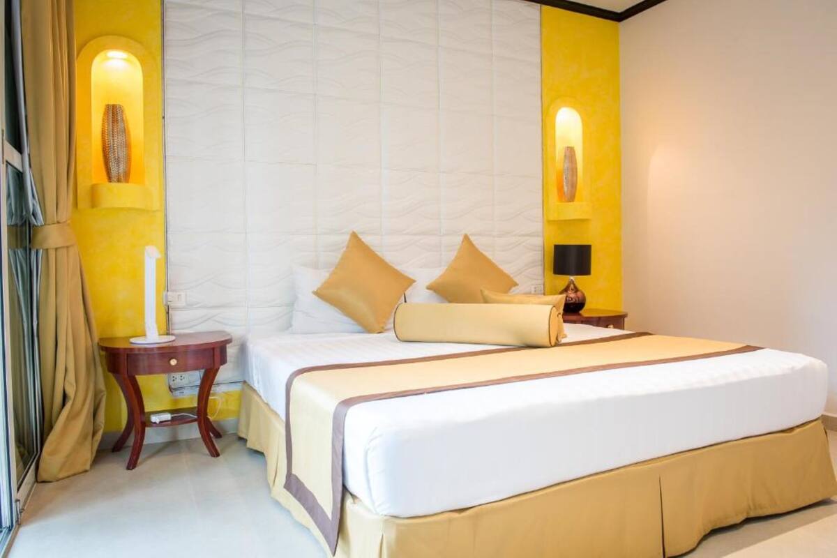 Une chambre d’hôtel avec un grand lit, deux tables de chevet et une petite table de nuit.
