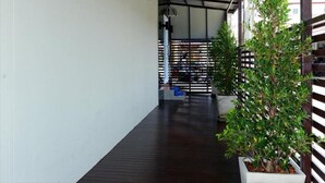 A covered walkway with a wooden floor, potted plants, and a metal fence. - My Living Place Samui (Koh Samui)