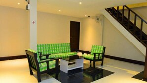 A modern living room with a black and white checkered sofa set, a small coffee table, and a staircase to the right. - My Living Place Samui (Koh Samui)