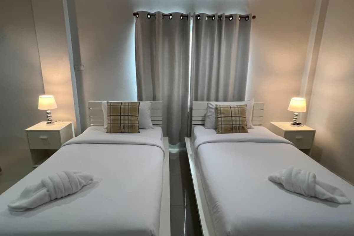 A twin room with two beds, each with a pillow and a towel, and bedside lamps.