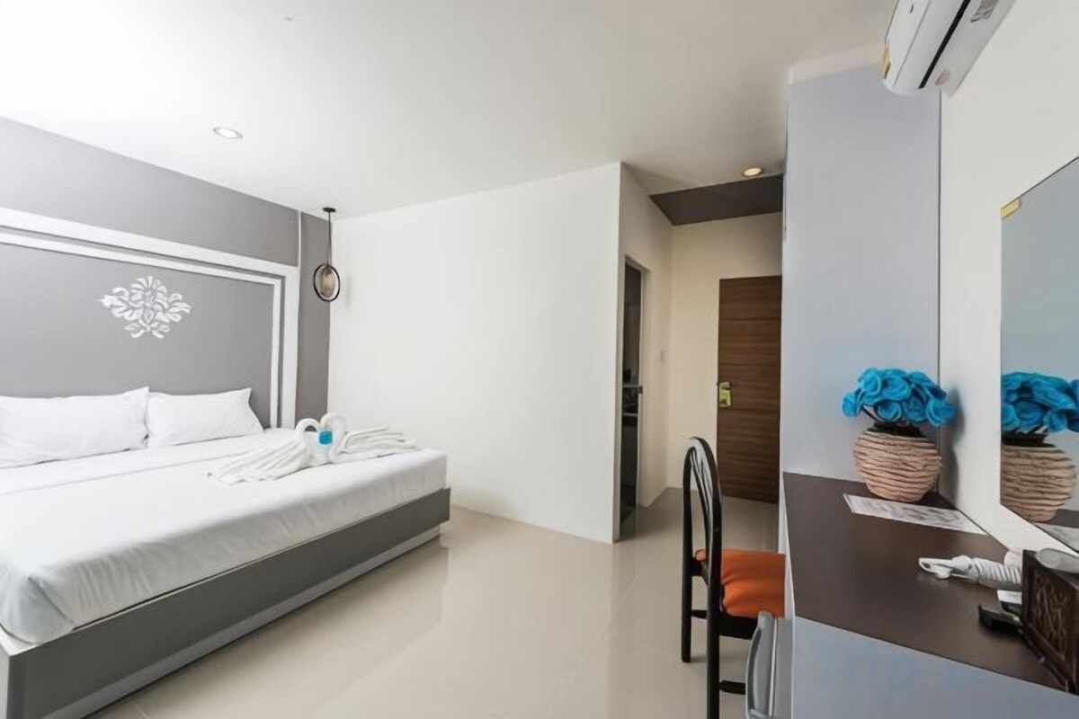 A modern hotel room with a bed, a desk, and a chair.