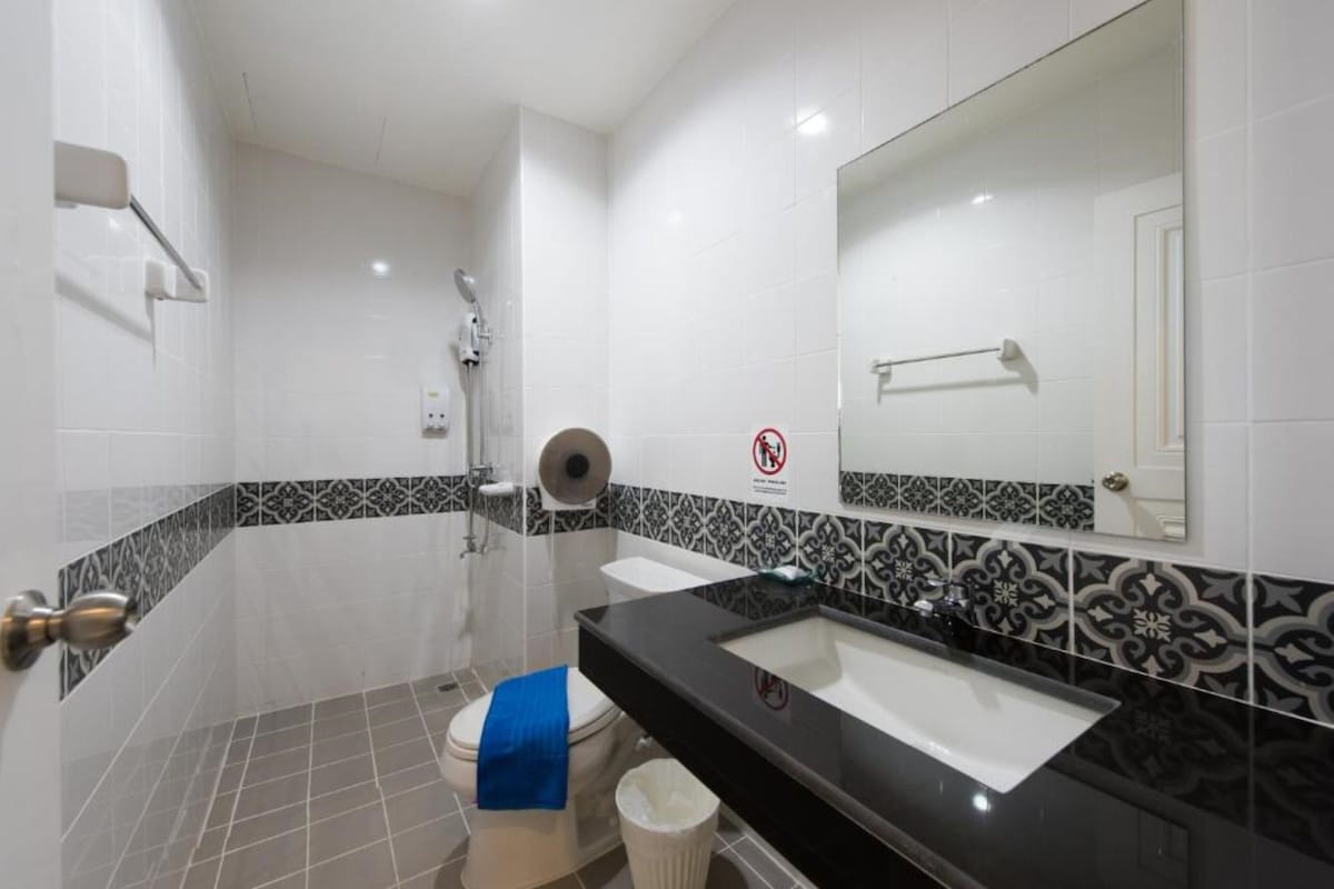 A bathroom with a black sink, white toilet, and a shower.