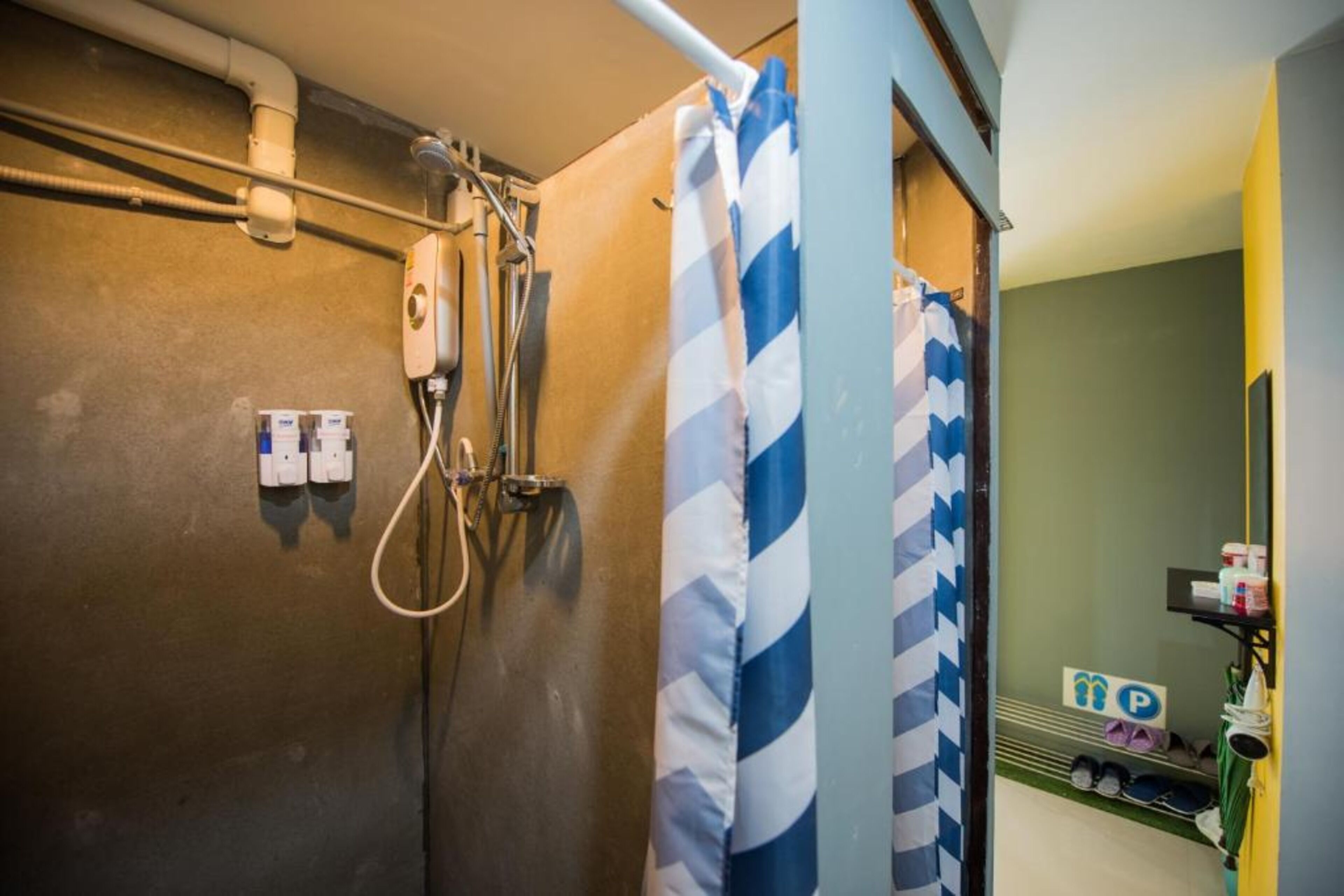 A shower area with a striped shower curtain, a handheld showerhead, and a wall-mounted control panel.