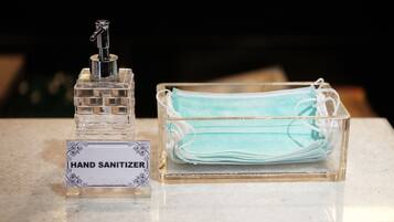 Um dispensador de álcool em gel e um recipiente de plástico transparente com máscara.