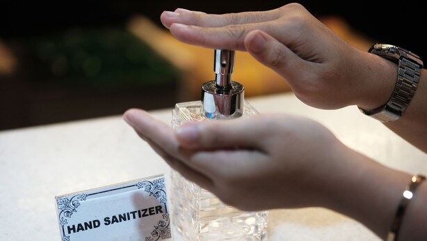 Ein Handdesinfektionsmittelspender auf einer Marmorplatte mit einem Schild, auf dem 'HAND SANITIZER' steht.