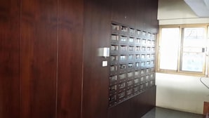 A room with a dark wooden wall and a metal filing cabinet with numbered compartments.