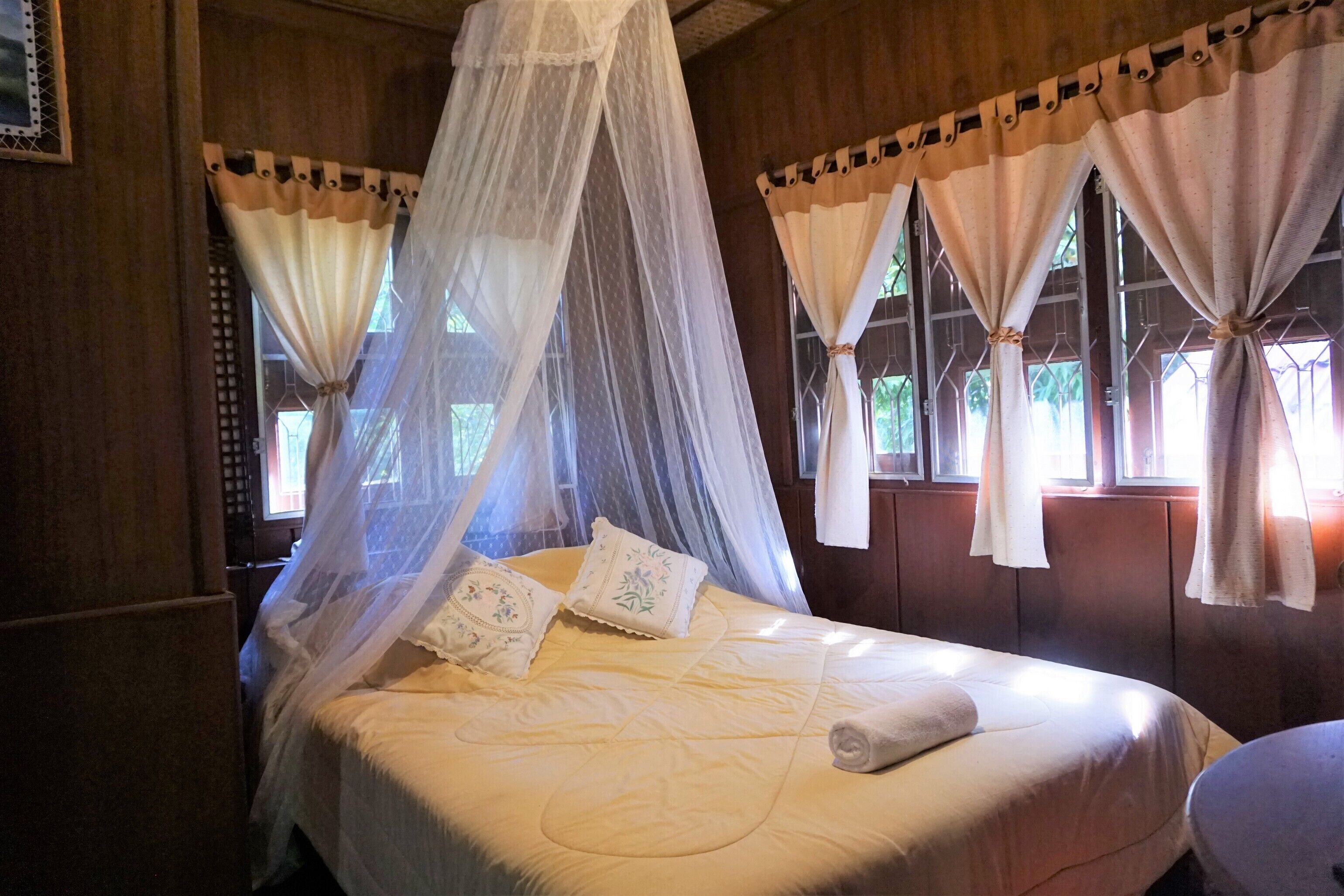 A bed with a canopy, pillows, and a rolled towel.