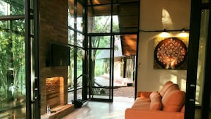 Un interior moderno con chimenea, un sofá y un ventanal con vistas al exterior.