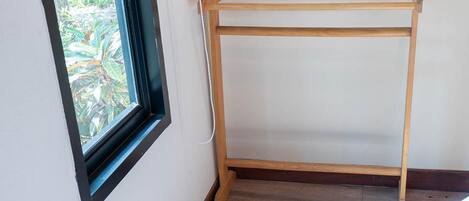 Un tendedero de madera apoyado contra una pared con una ventana.