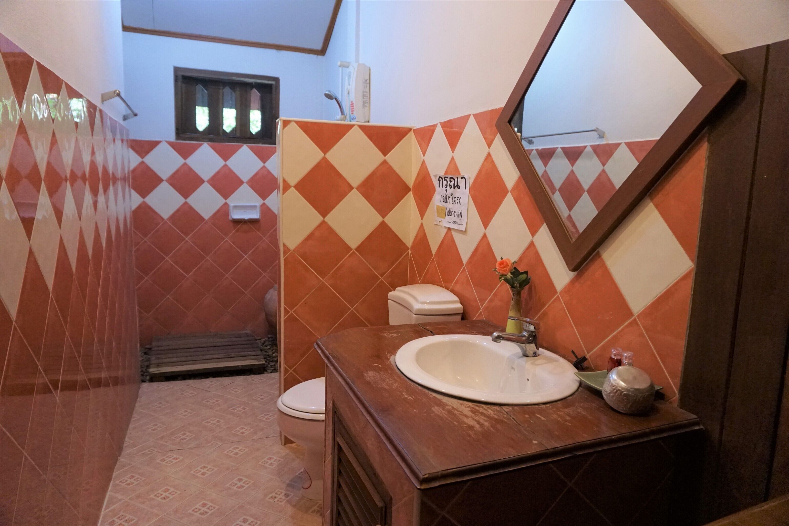 A bathroom with a tiled floor, a sink with a mirror, and a toilet.