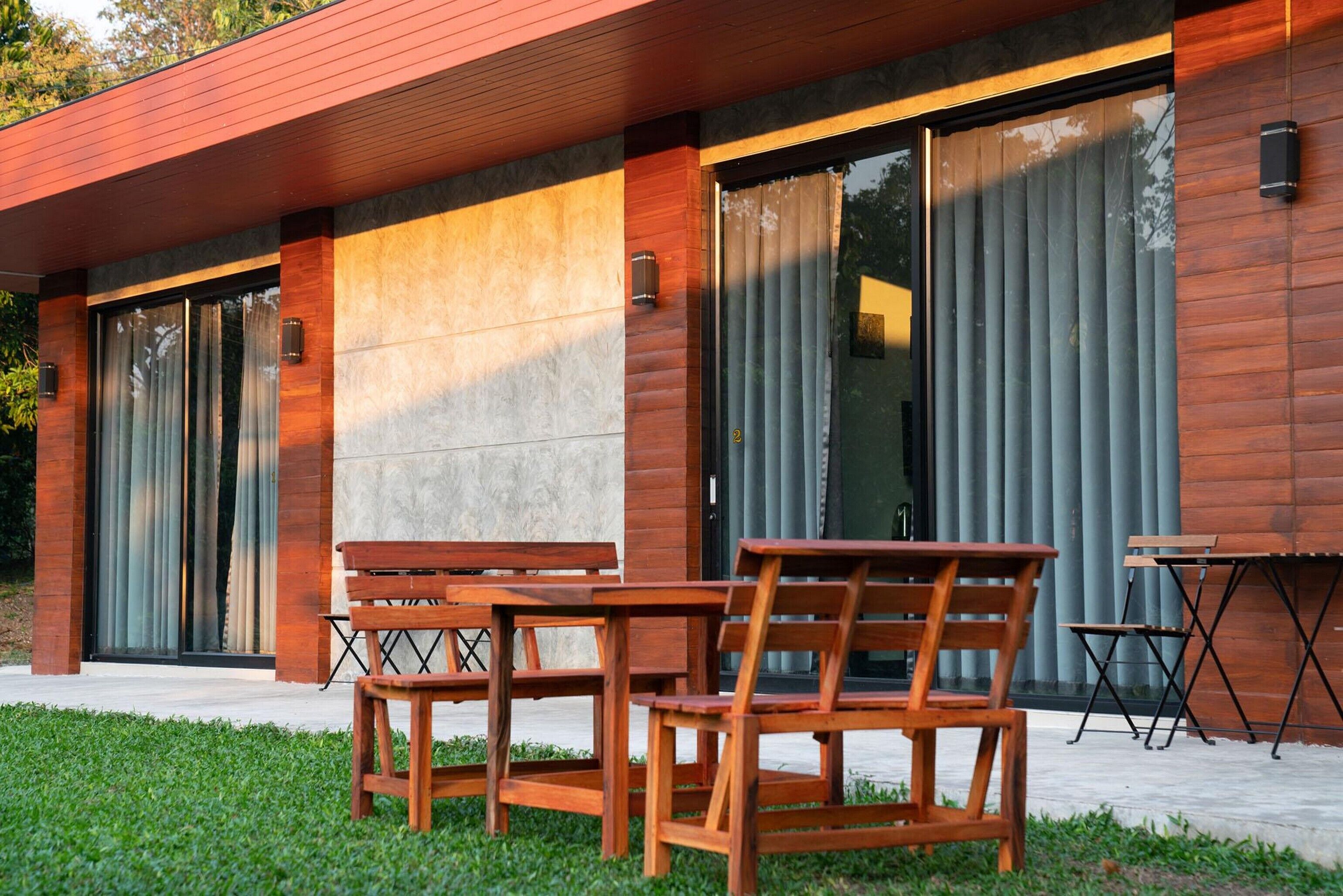 A modern building with large windows, a wooden exterior, and outdoor seating.