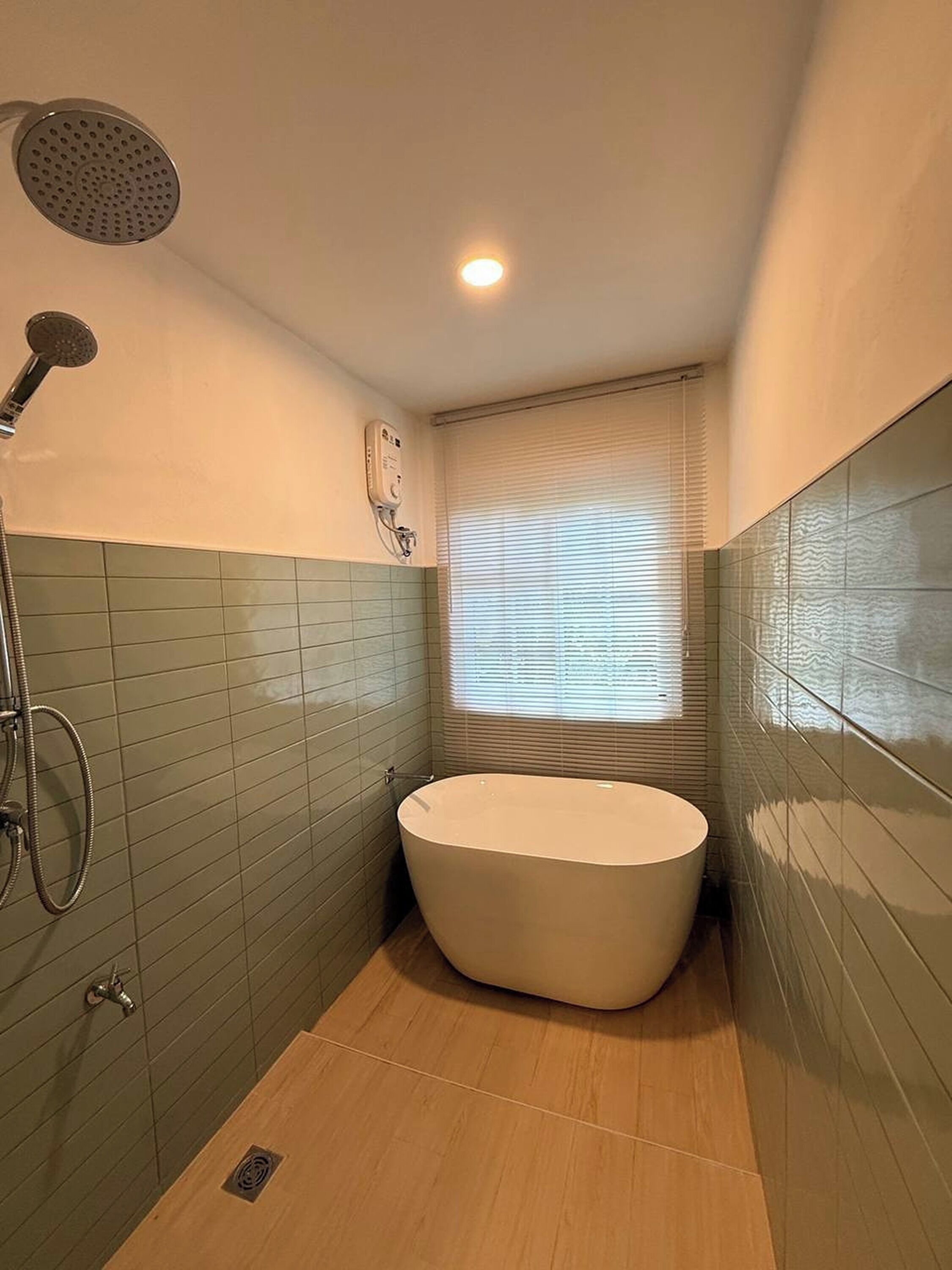 A bathroom with a freestanding bathtub, a handheld showerhead, and a wall-mounted control panel.