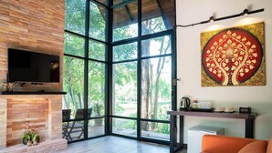 Una sala de estar moderna con chimenea, un ventanal grande y un cuadro de un árbol.