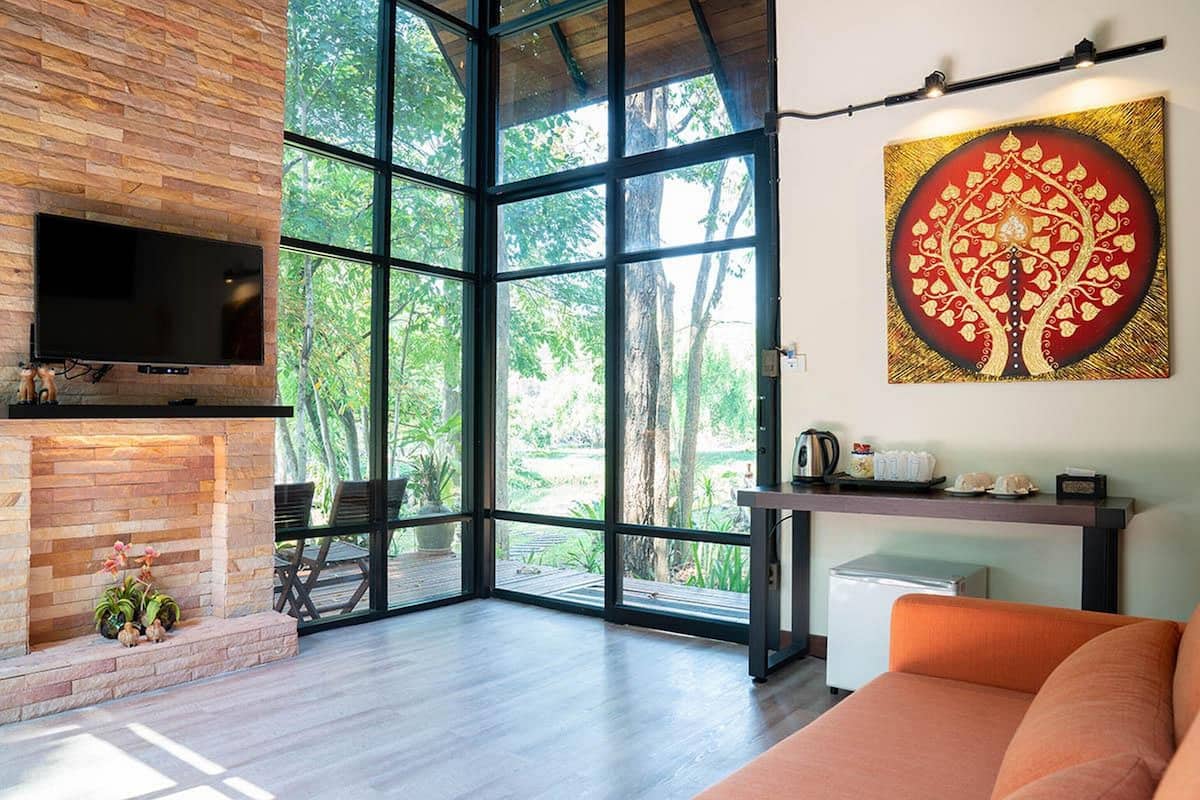 A modern living room with a fireplace, a large window, and a painting of a tree.