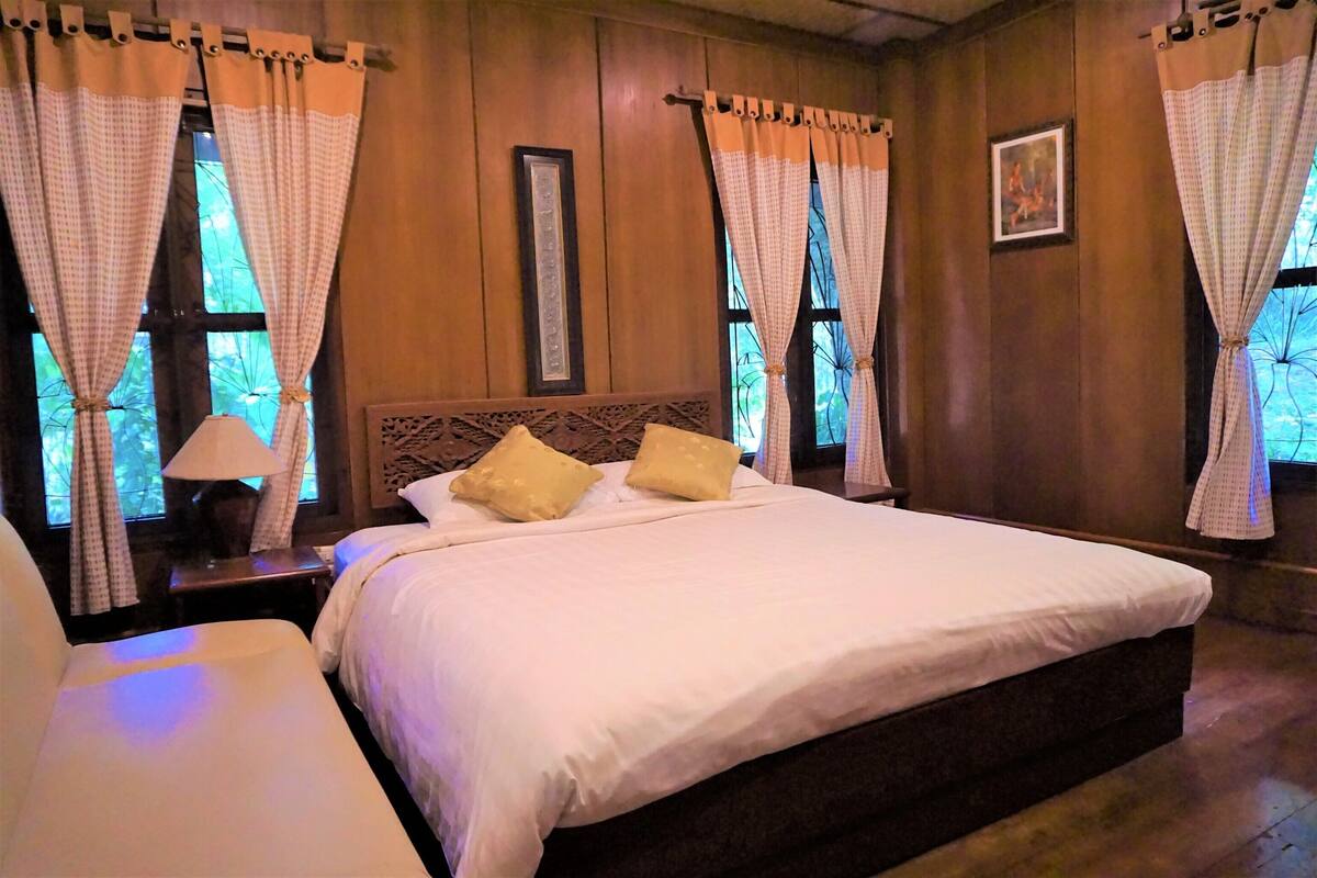 A bedroom with a large bed, two bedside tables, and curtains.