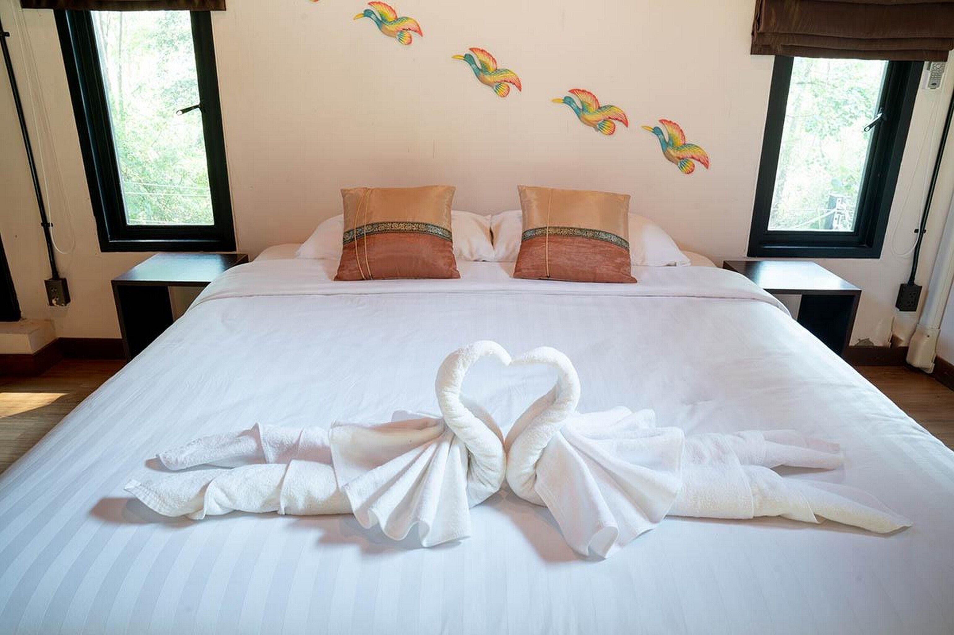 A hotel room with a large bed, two pillows, and a heart-shaped towel arrangement.