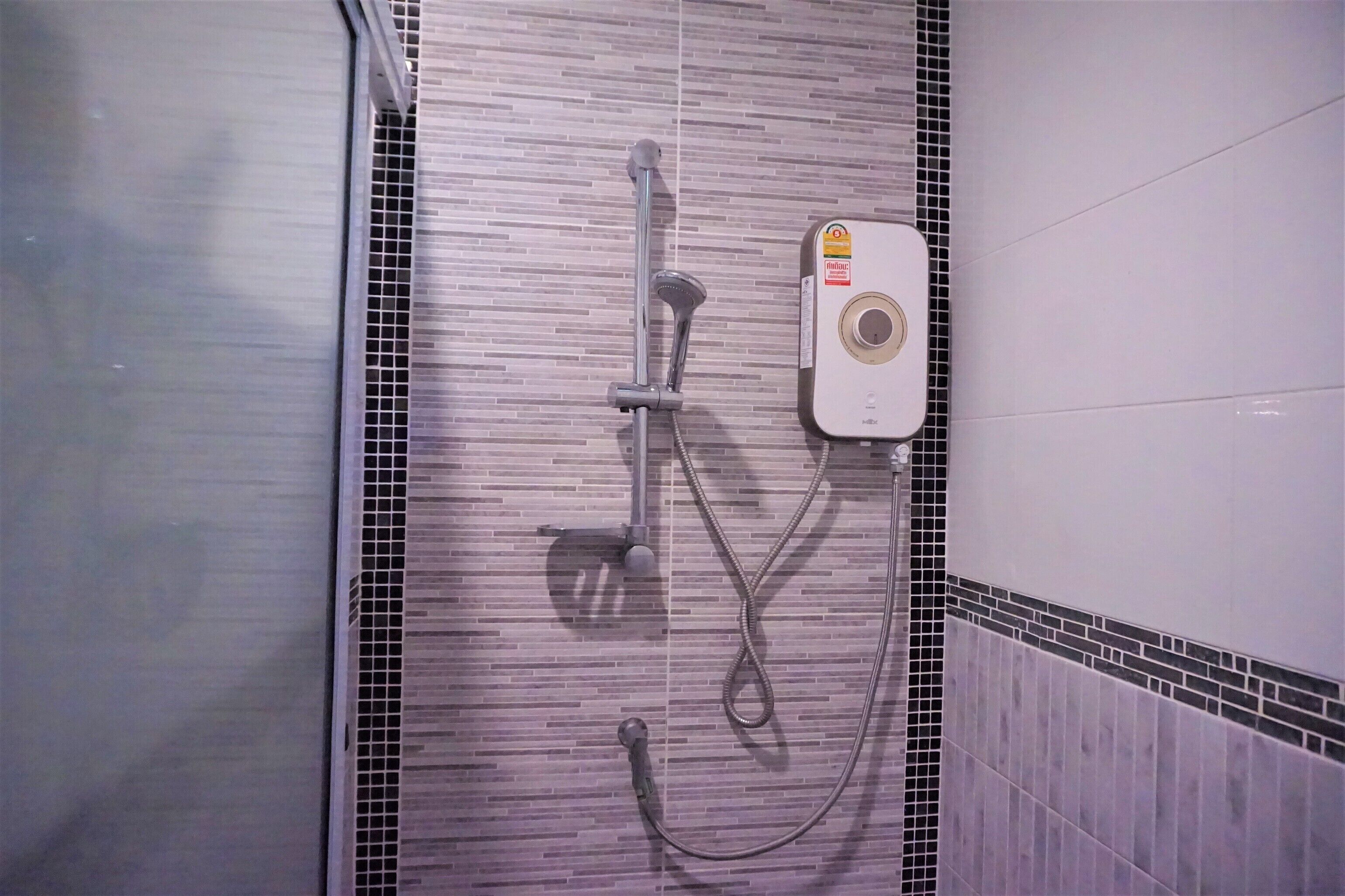 Un área de ducha con cabezal de ducha de mano, cabezal de ducha fijo y panel de control.