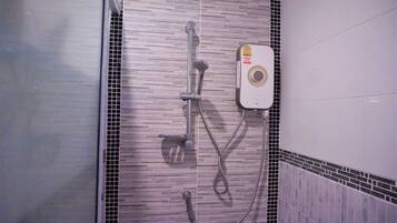 Un área de ducha con cabezal de ducha de mano, cabezal de ducha fijo y panel de control.