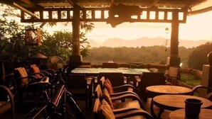 Un espace extérieur aménagé avec des meubles et des tables en bois, offrant une vue sur un paysage montagneux.
