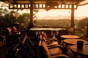 Un área de estar al aire libre con muebles y mesas de madera, con vistas a un paisaje montañoso.