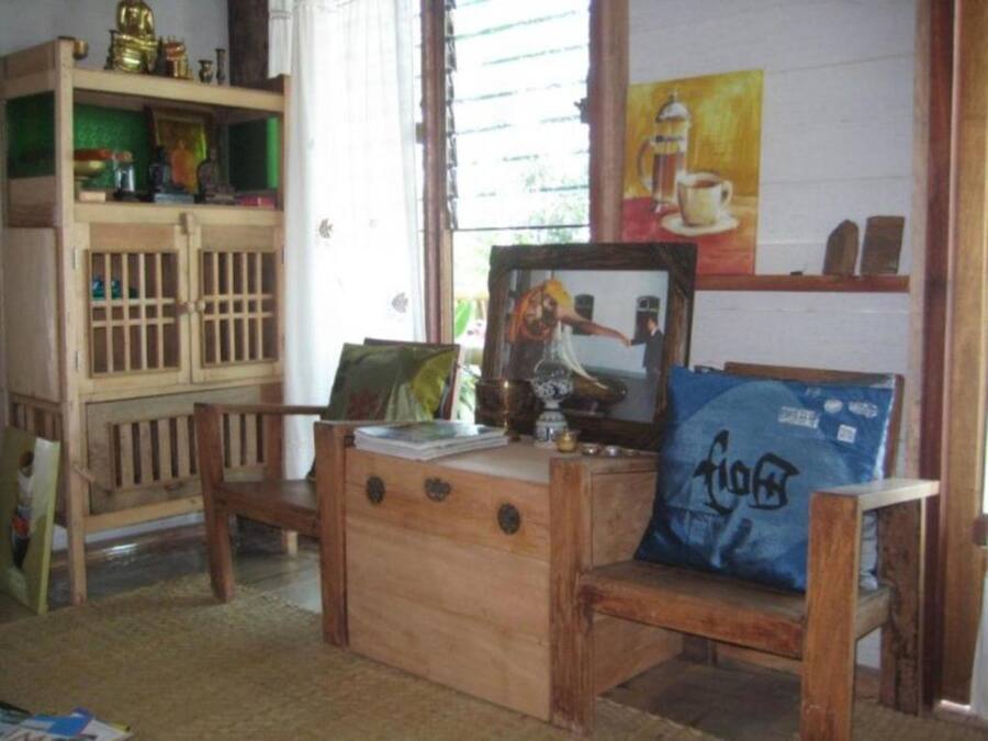 Quarto aconchegante com uma escrivaninha de madeira, uma cadeira e uma prateleira com diversos objetos.