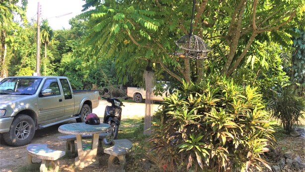 A pickup truck parked in a garden with a motorcycle and a table. - AP Hotel (Ao Luek)