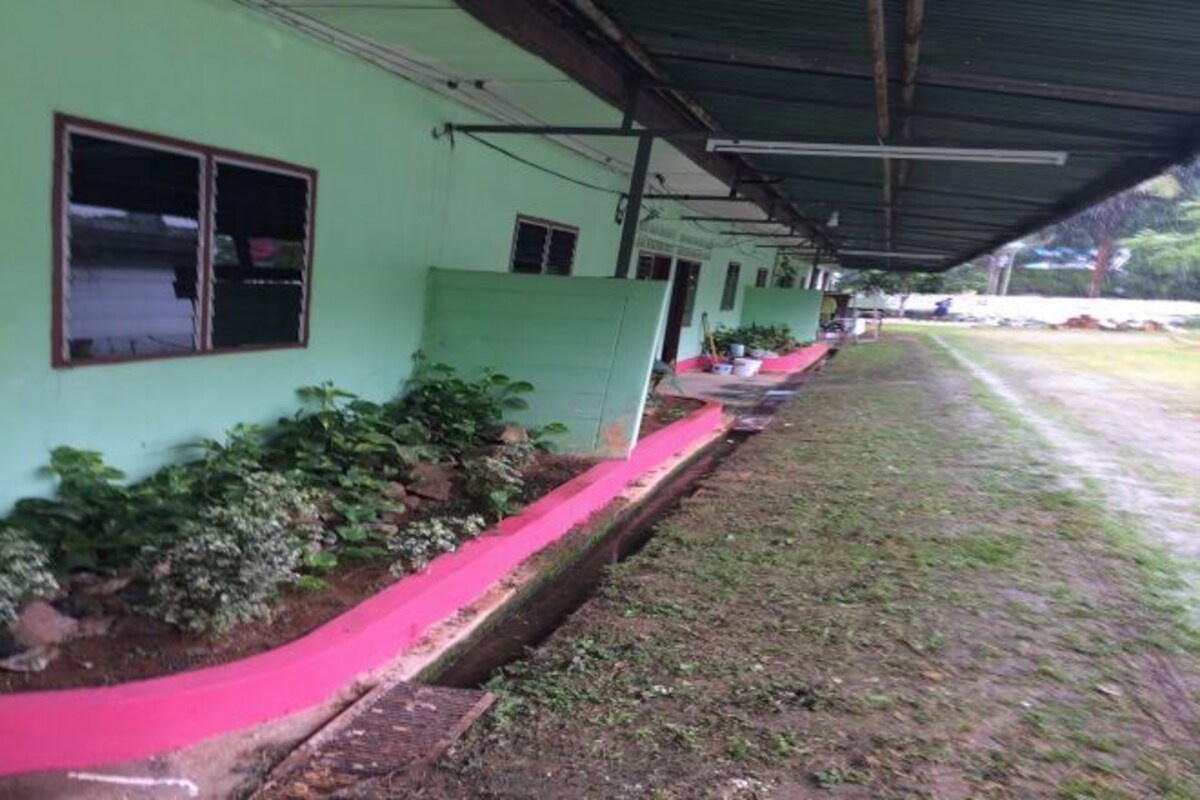 Un edificio con fachada verde y una galería techada.