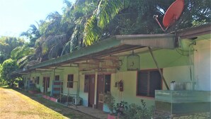 A row of single-story buildings with a simple, functional design, featuring a central corridor and individual rooms with small windows. - AP Hotel (Ao Luek)