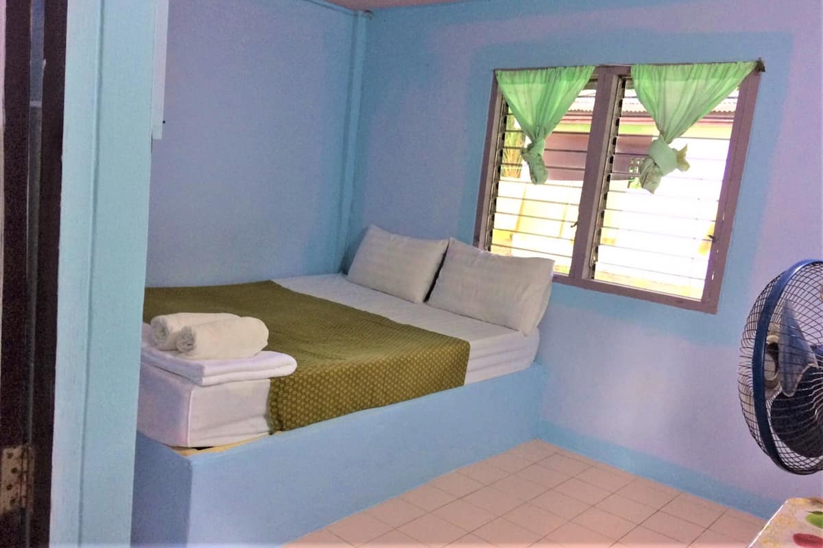 A small, single-bed room with a window and a fan.