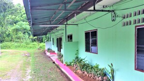 A green building with a covered porch, windows, and a small garden area. - AP Hotel (Ao Luek)