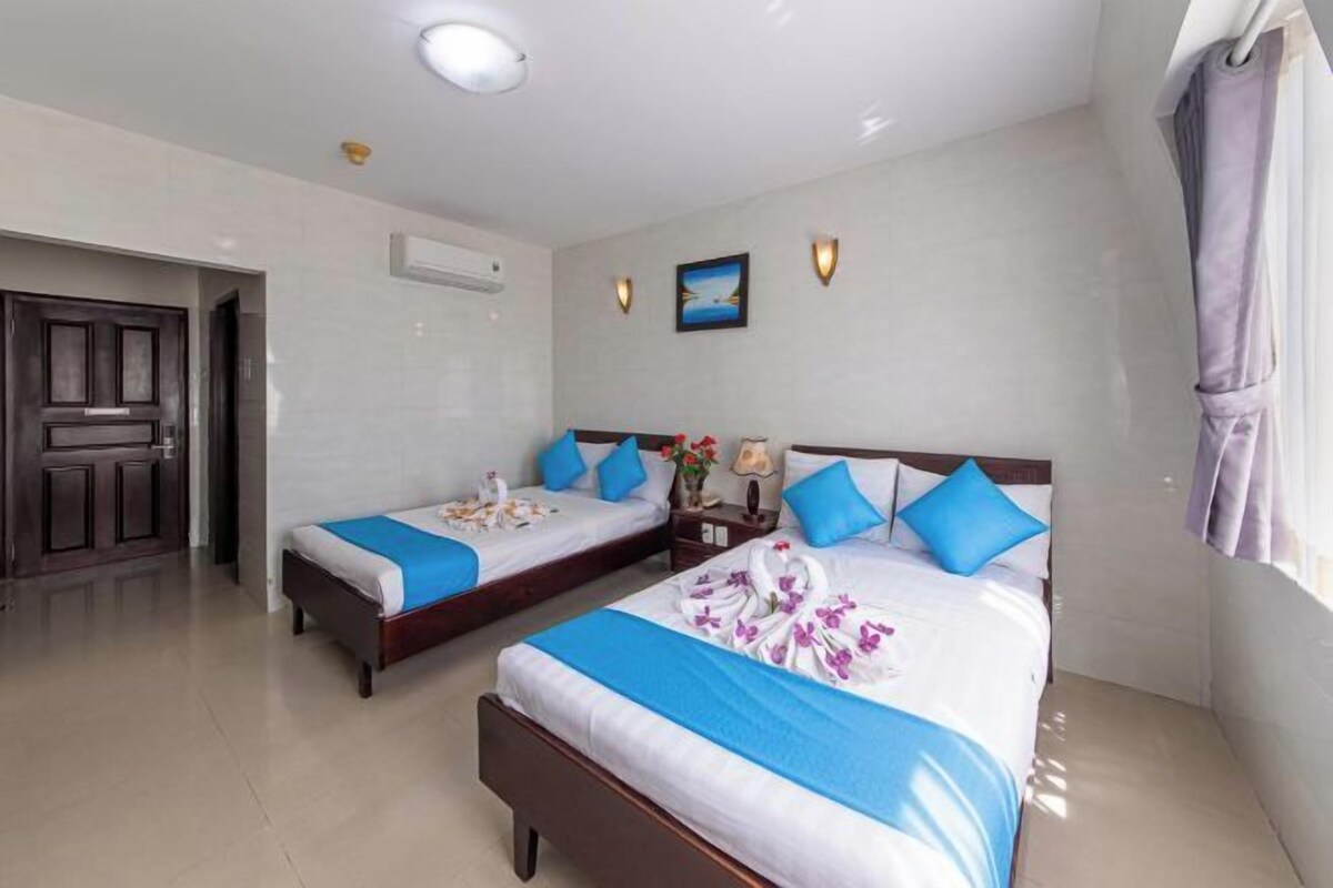 A hotel room with two beds, a door, an air conditioning unit, and a wall-mounted picture.