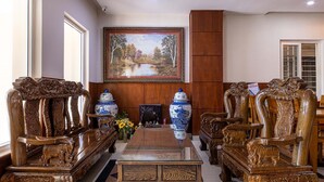 Una habitación tradicional con muebles de madera ornamentada, un cuadro grande en la pared y dos jarrones azul y blanco sobre la mesa.
